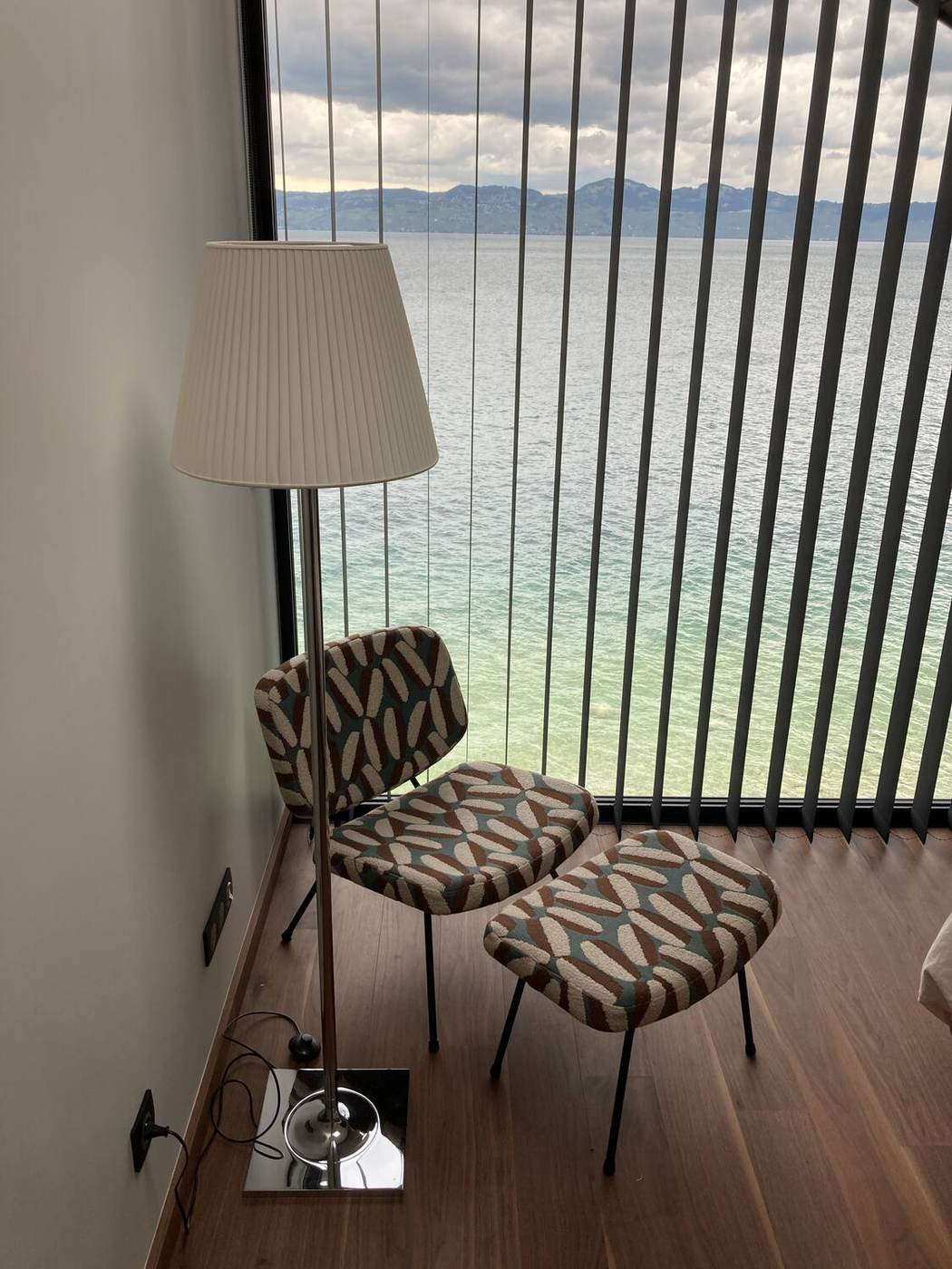 Claustra verticale devant la baie vitrée, fauteuil et parquet